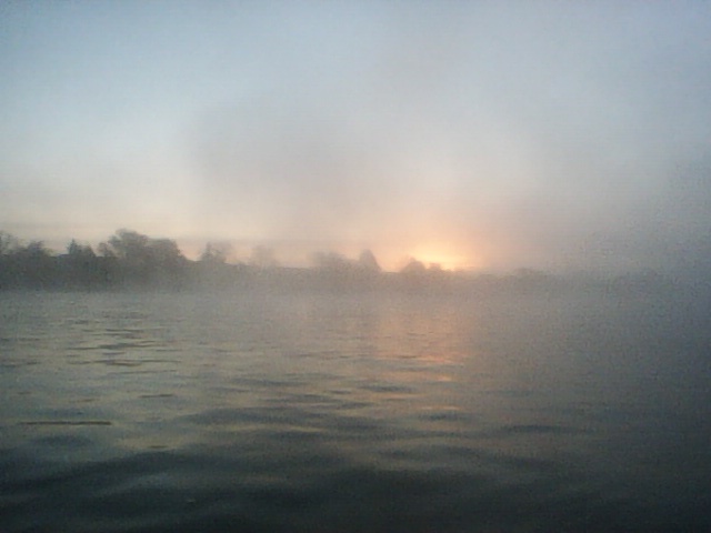 A sunrise behind a misty river.